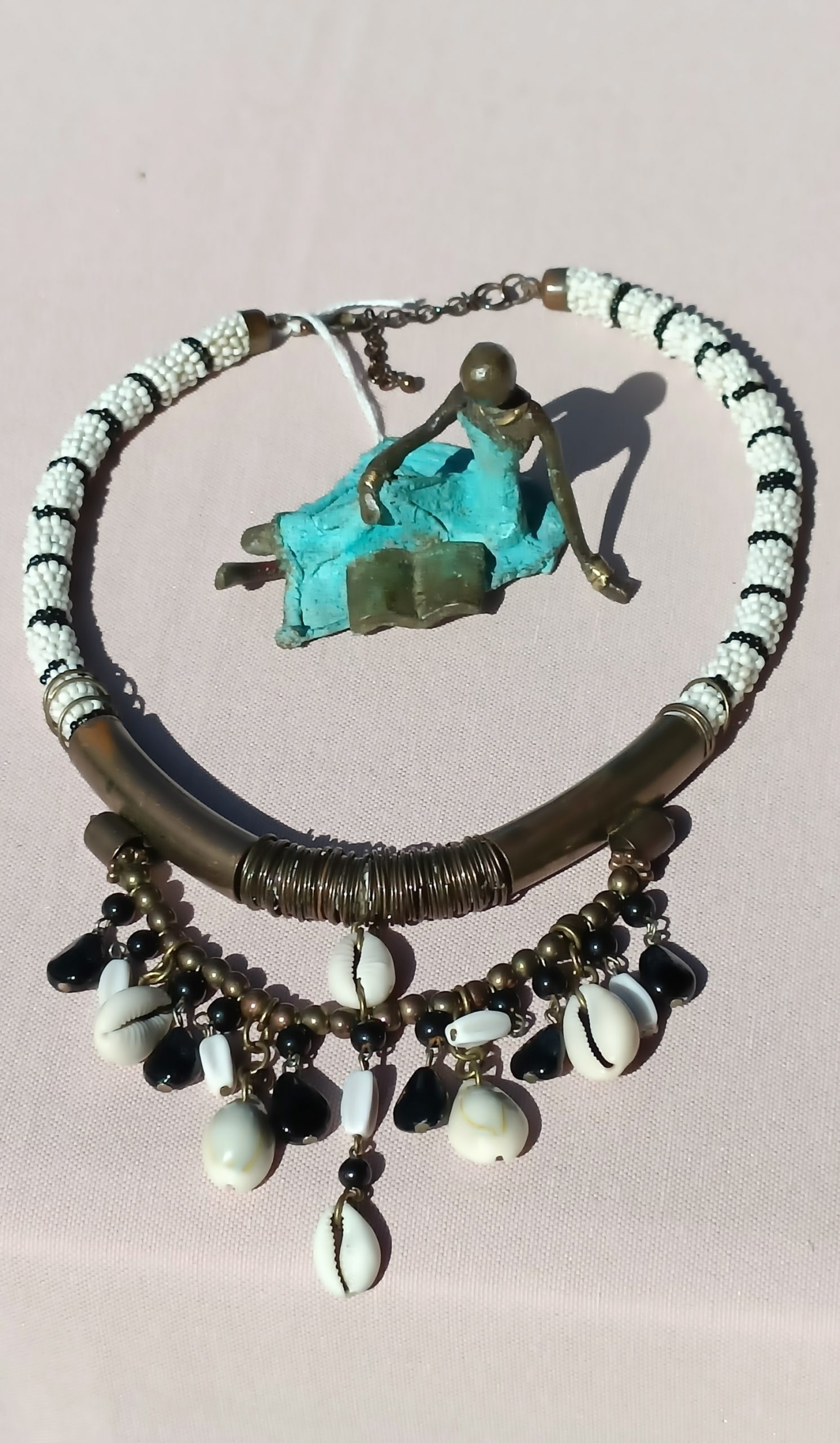 collier ethnique avec perles de rocaille noires et blanches, pièce métallique et coquillage cauris.